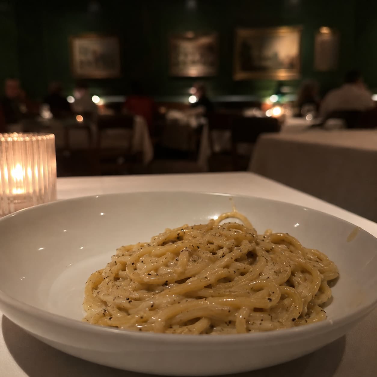 A bowl of vegan cacio e pepe shot on a phone, pale and flatly lit
