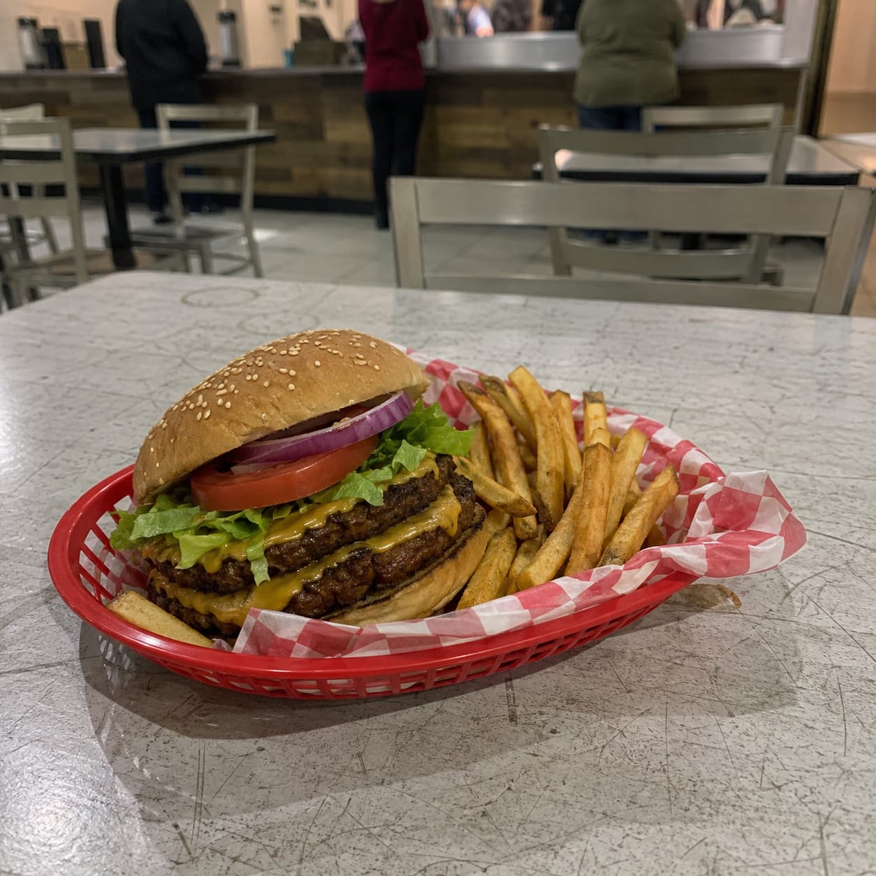 A vegan smash burger photographed on a phone, the bun pale and the lettuce dull