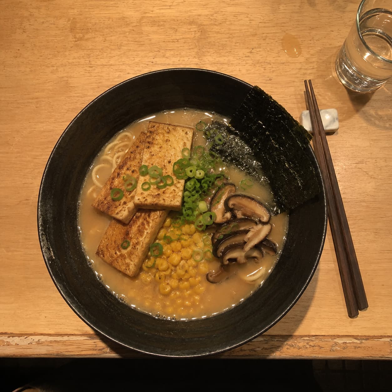 A bowl of vegan miso ramen photographed on a phone, steam and detail lost